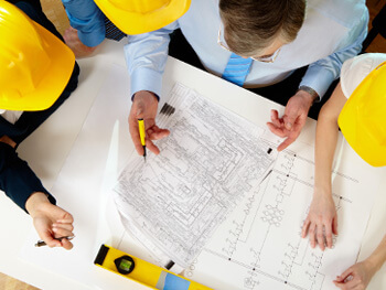 Several construction workers and project managers reviewing blue prints