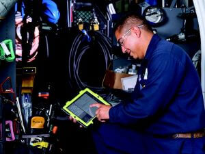 HVAC technician using tablet to assess HVAC equipment
